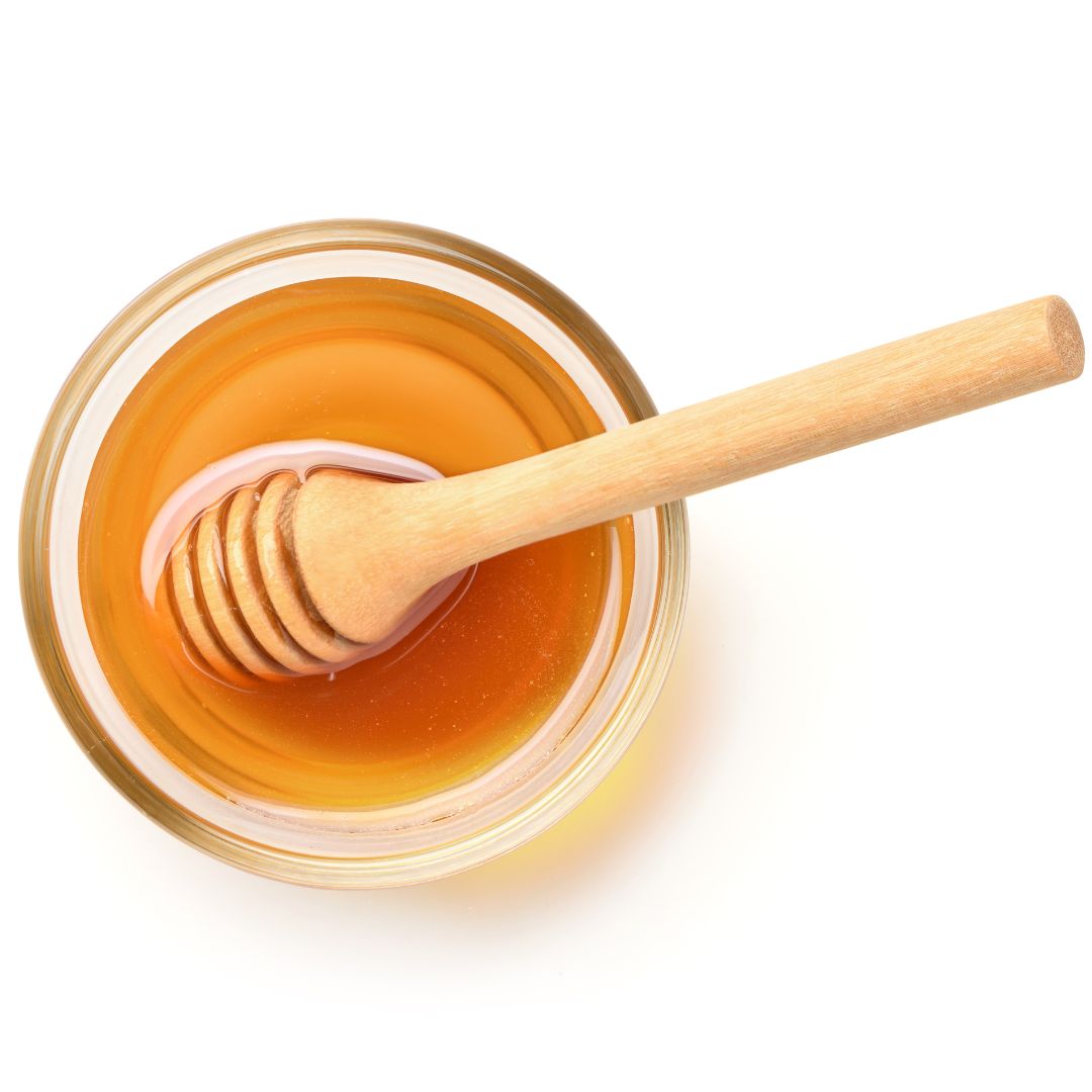 Ciotola di vetro con miele e cucchiaio di legno. Vista dall'alto.