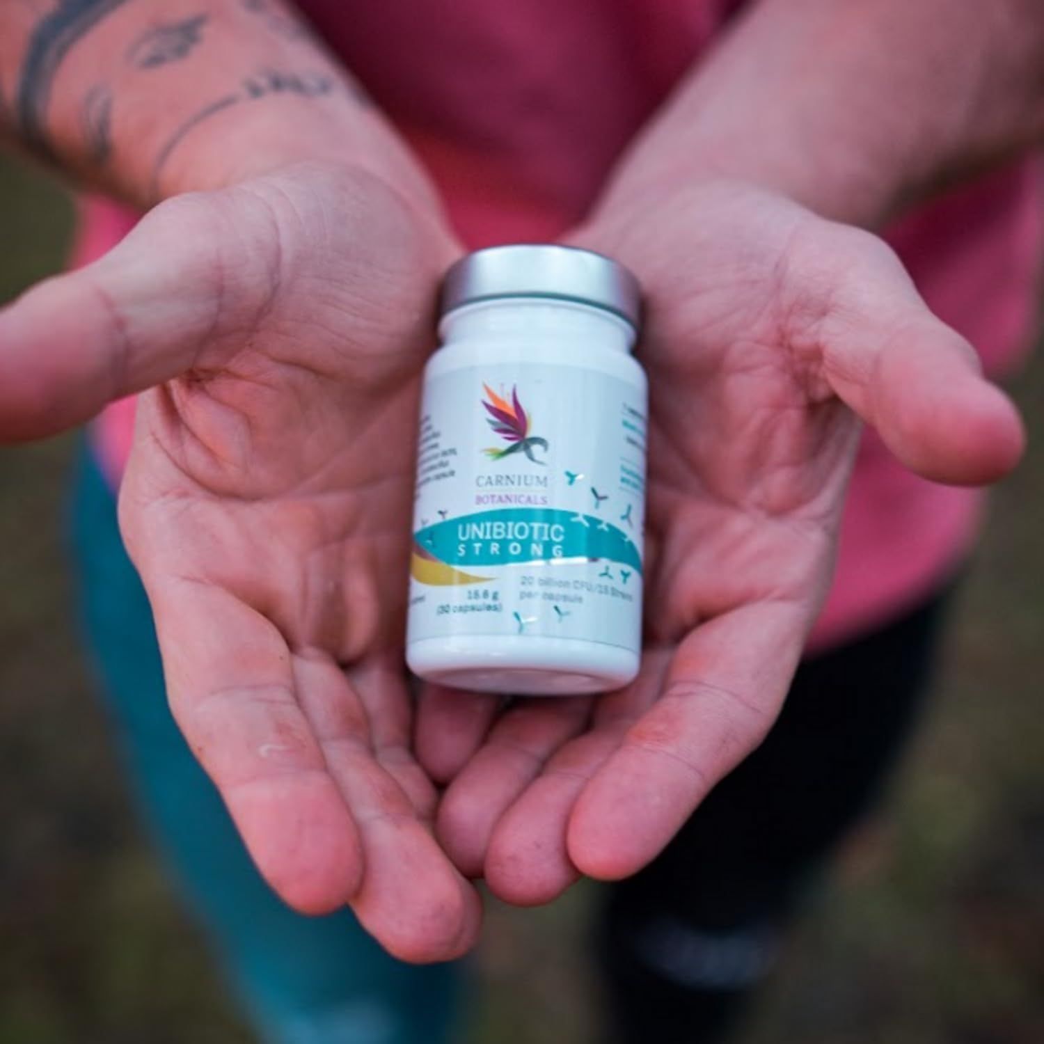 Flacone con capsule in mano. Scritta: Unibiotic STRONG, 20 miliardi di CFU/15 ceppi. Marchio: CARNIUM BOTANICALS.