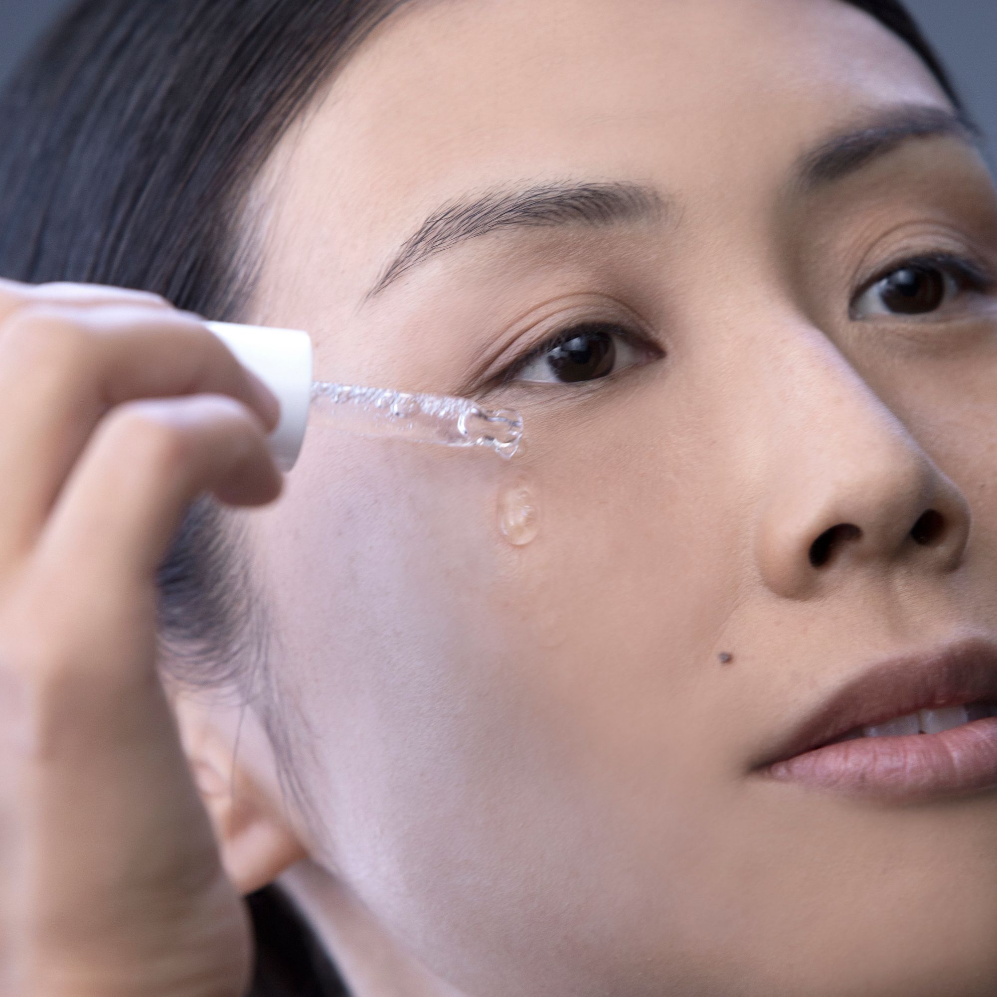 Una donna si applica il siero Alkemy Pure Collagen vicino all'occhio con un contagocce.
