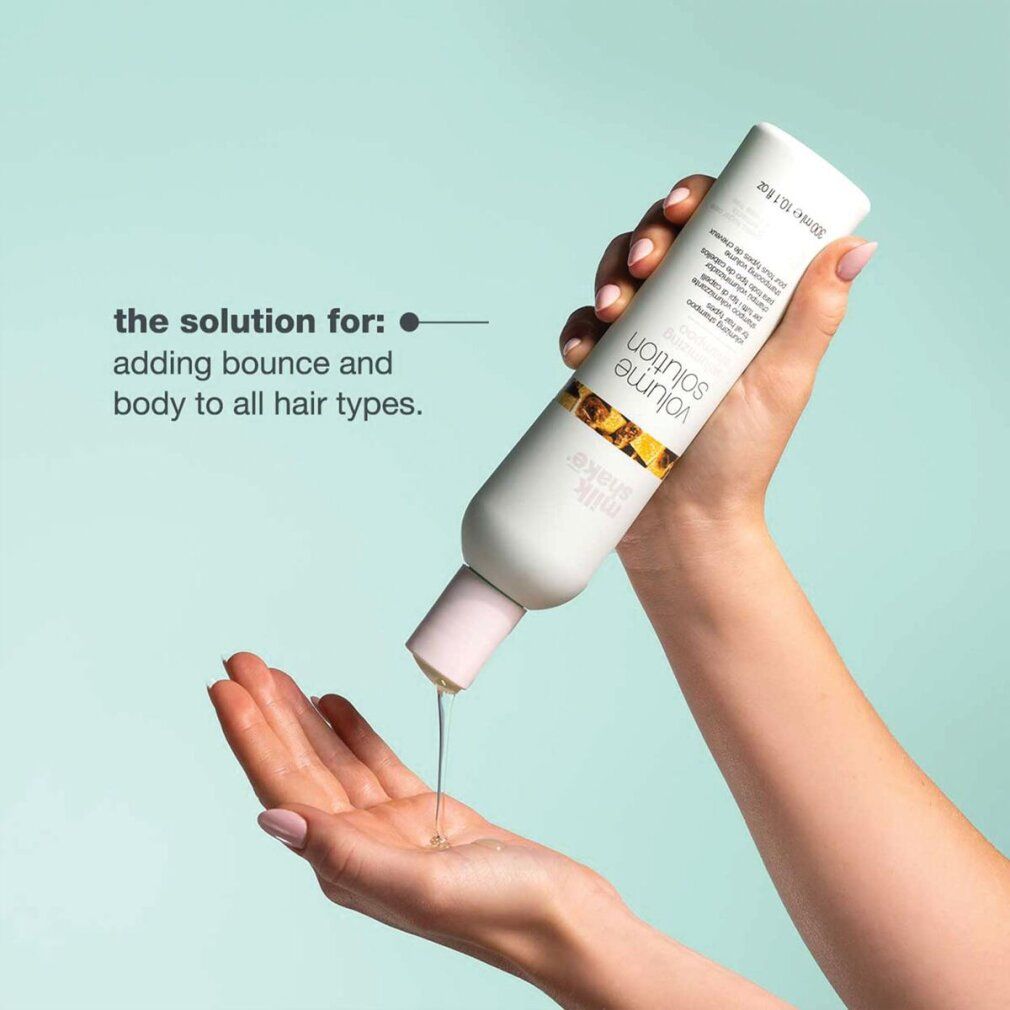 Una mano tiene un flacone bianco Milk_Shake Volume Solution. Liquido versato nell'altra mano.
