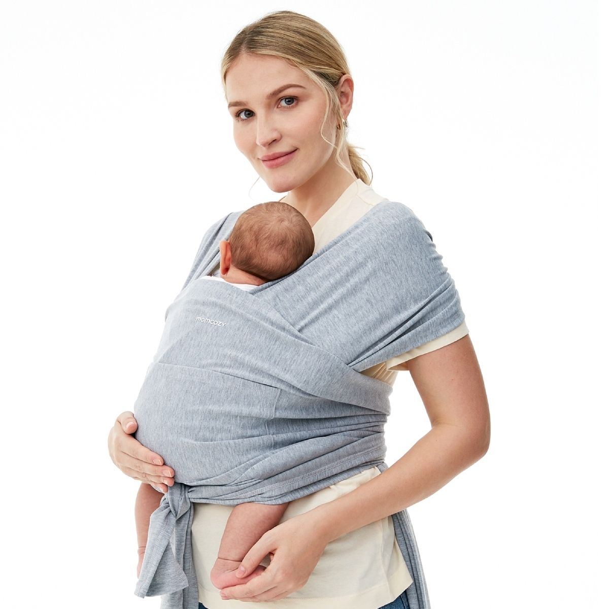 Una fascia porta bebè Momcozy grigia indossata da una donna che tiene in braccio un bambino. La fascia è avvolta attorno al corpo della donna, il bambino è tenuto al sicuro. Il logo Momcozy è visibile sulla fascia.