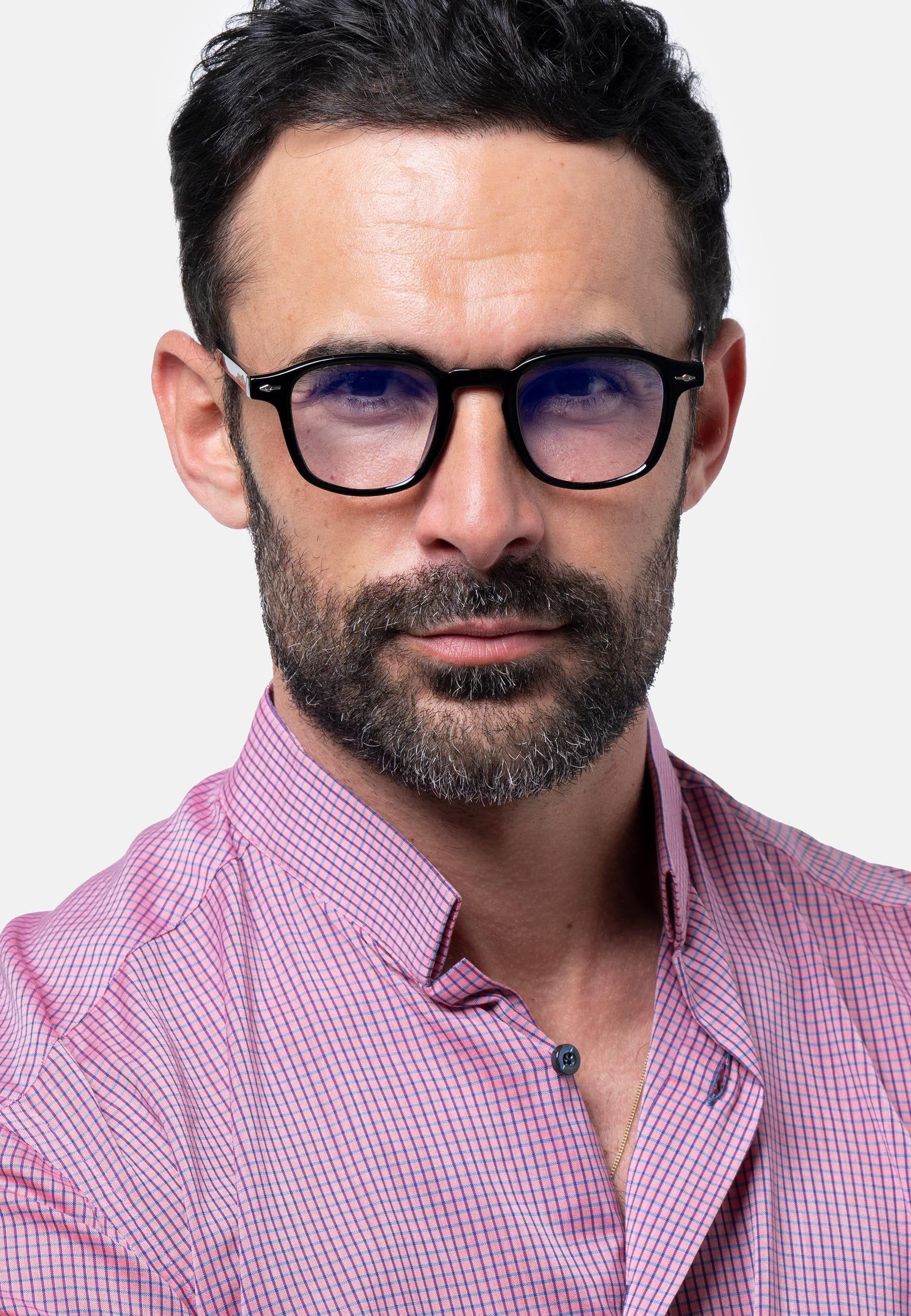 Uomo con occhiali neri. Gli occhiali hanno lenti quadrate. L'uomo indossa una camicia rosa.