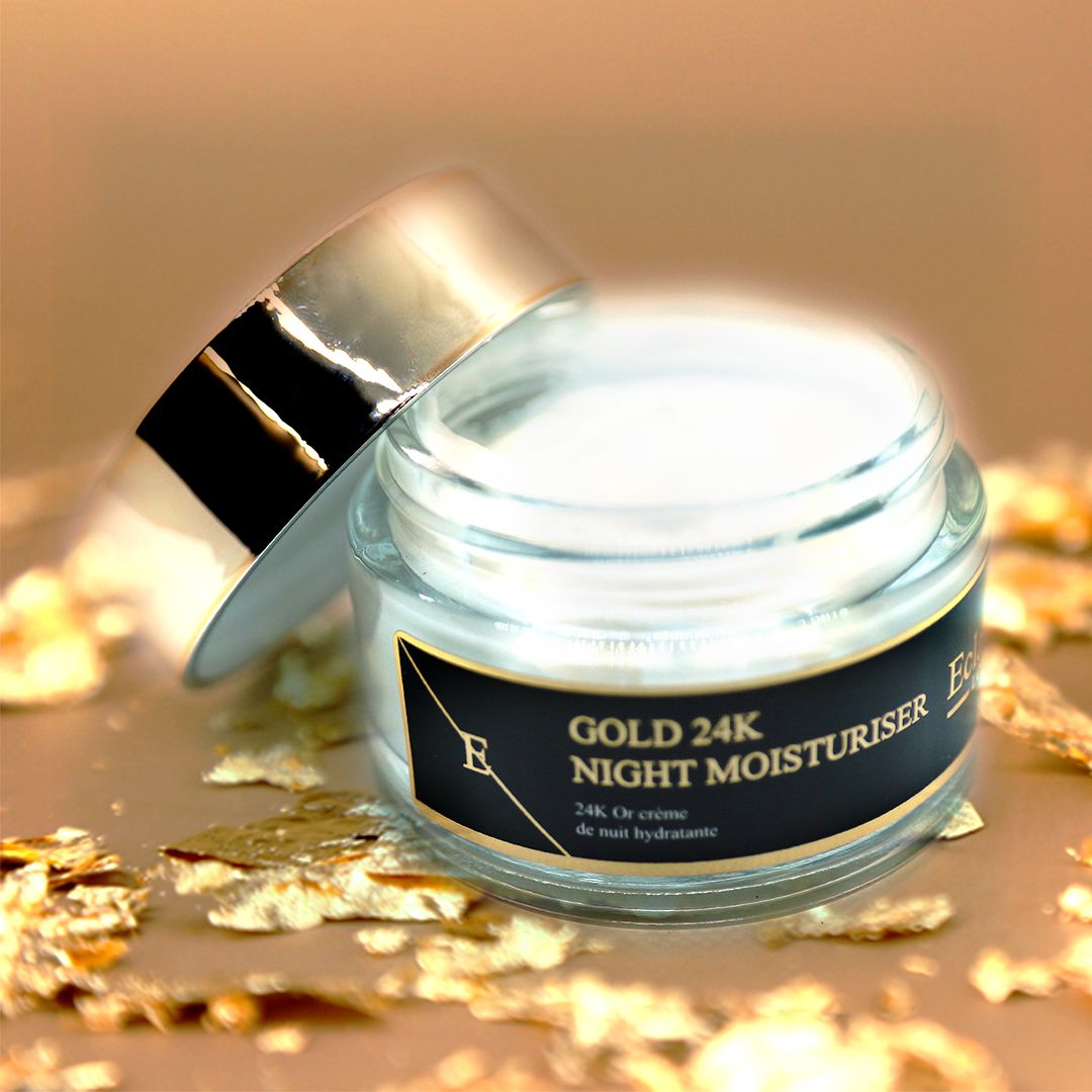 Vaso di crema con coperchio dorato, aperto. Scritta: GOLD 24K NIGHT MOISTURISER. Circondato da foglie d'oro.