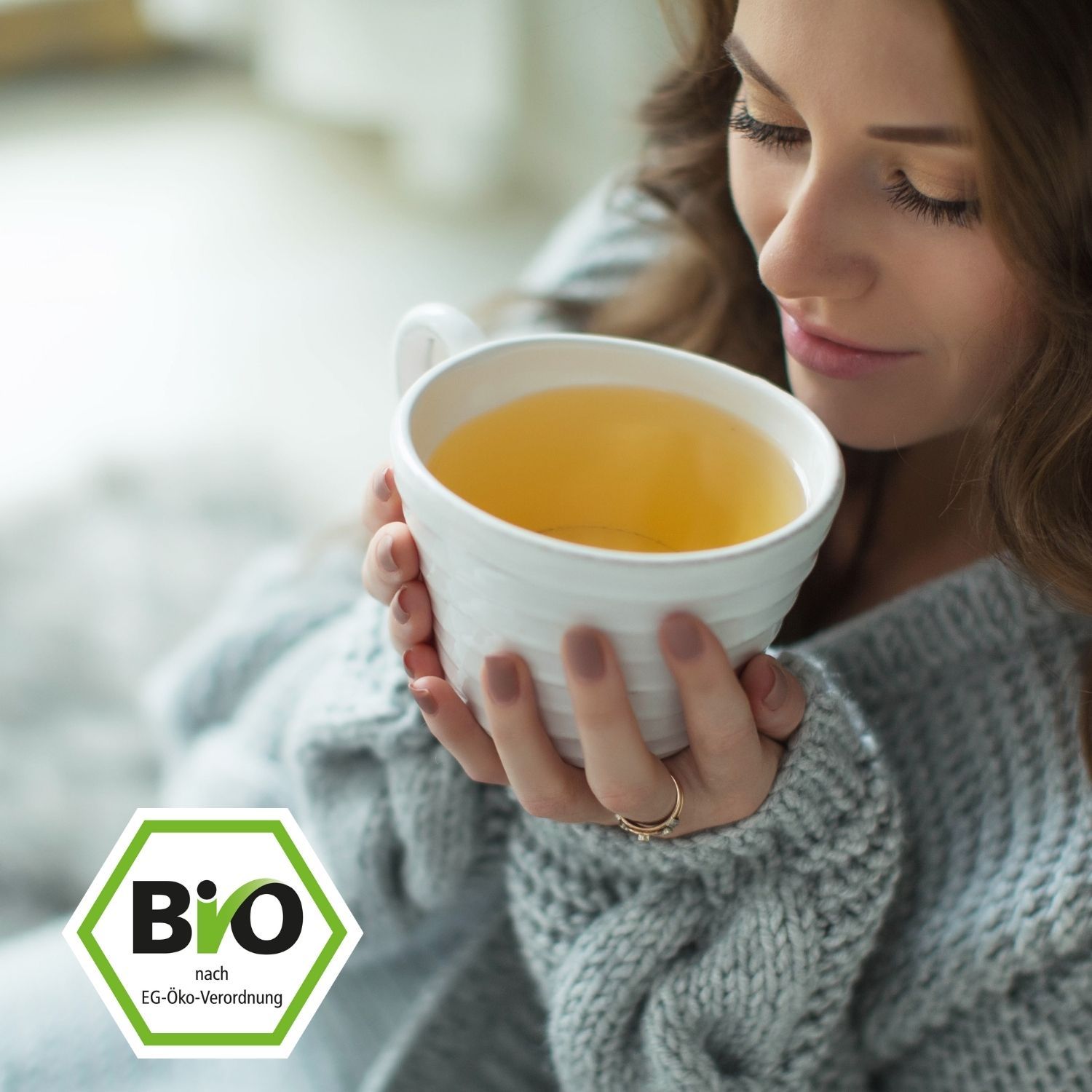 Donna tiene una tazza di tè bianca. Etichetta bio in primo piano.