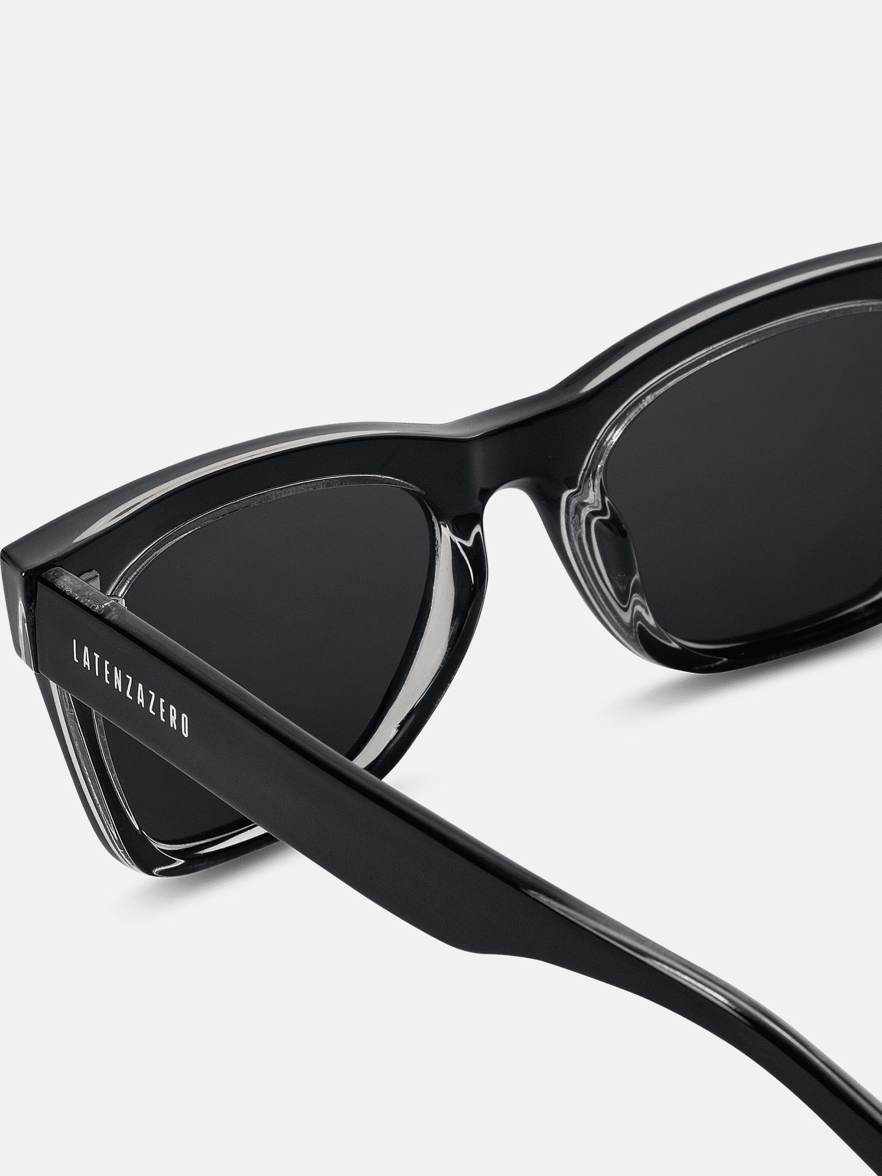 Primo piano di occhiali da sole neri con lenti squadrate. Il nome del marchio è visibile sulla stanghetta.