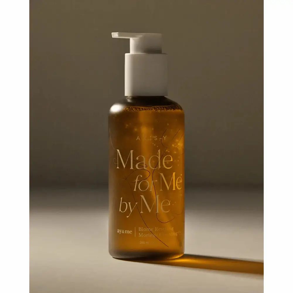 Flacone marrone con erogatore bianco. Scritta: AXIS-Y, Made for Me by Me, Biome Resetting Moringa Cleansing Oil.