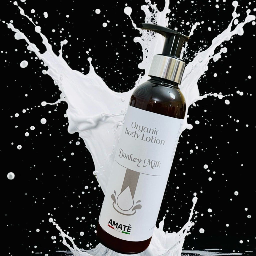 Flacone marrone con dosatore davanti a schizzo di latte bianco. Scritta: Organic Body Lotion Donkey Milk. Marchio: AMATÈ.