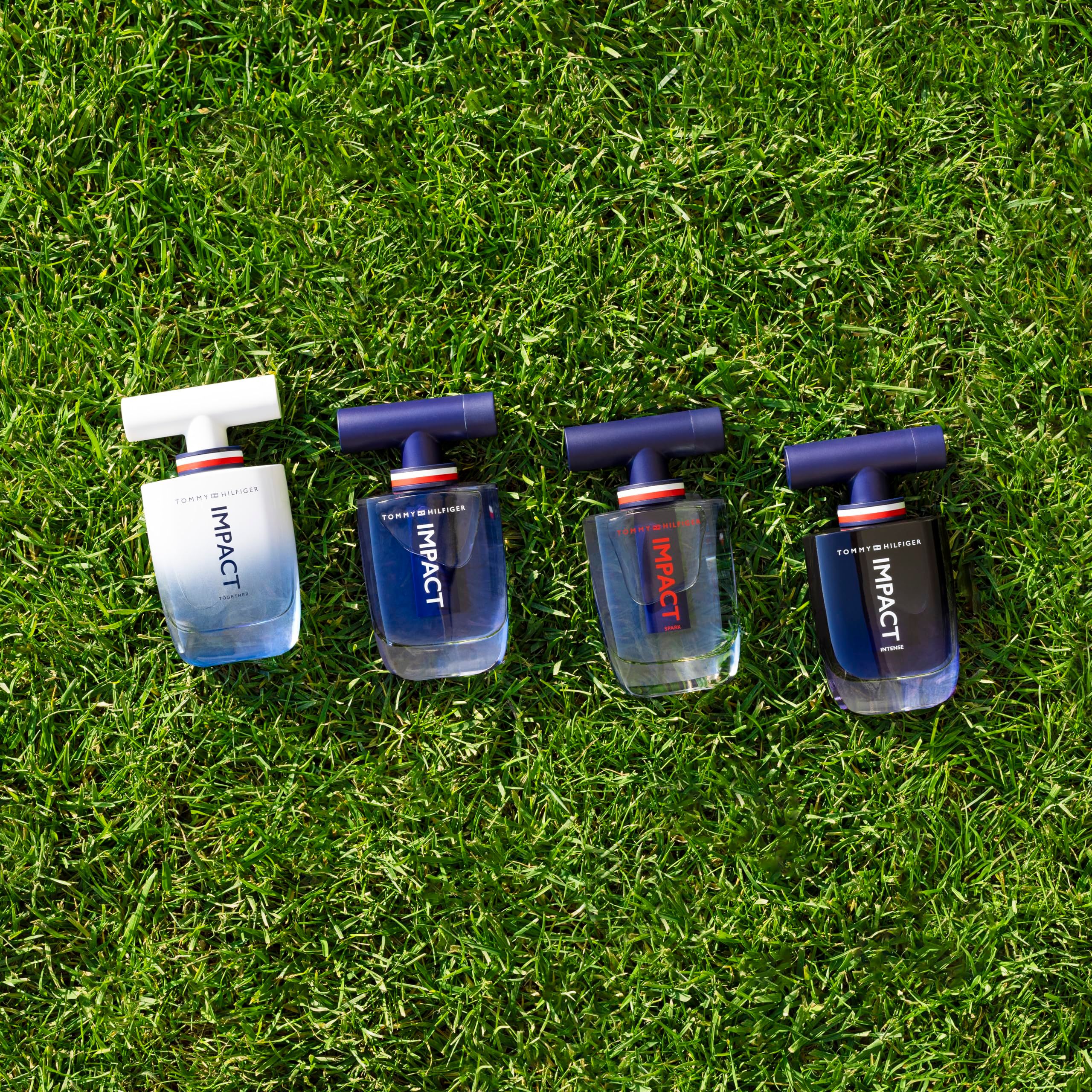 Quattro flaconi Tommy Hilfiger Impact Together sull'erba. Sfumature da blu a bianco. Scritta IMPACT.