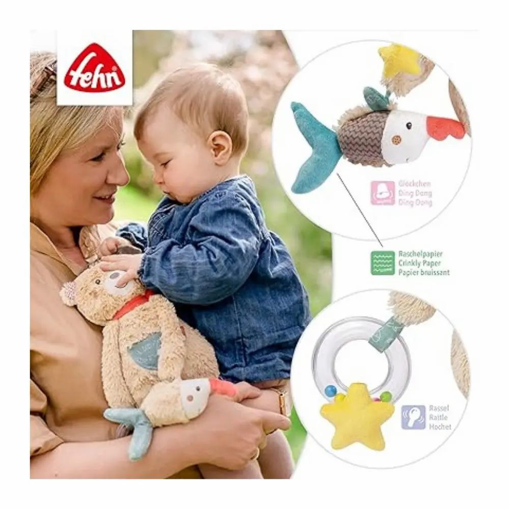 Bambino tiene peluche con pesce. Peluche con cappello, sciarpa rossa, stella. Marchio: fehn. Con testo.