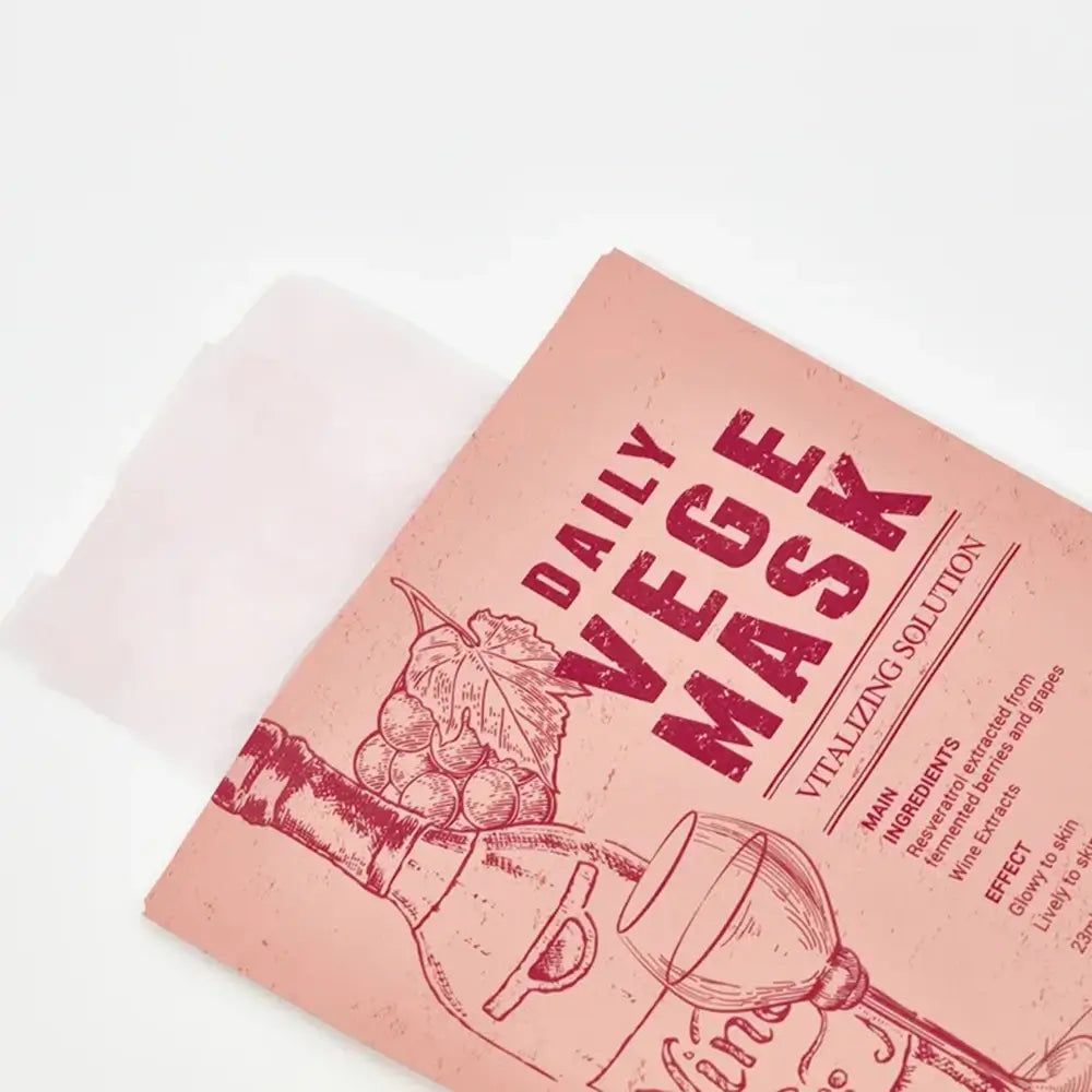 Confezione rosa parzialmente aperta. Stampa: DAILY VEGE MASK, illustrazione del vino, ingredienti, effetto. Maschera bianca visibile.
