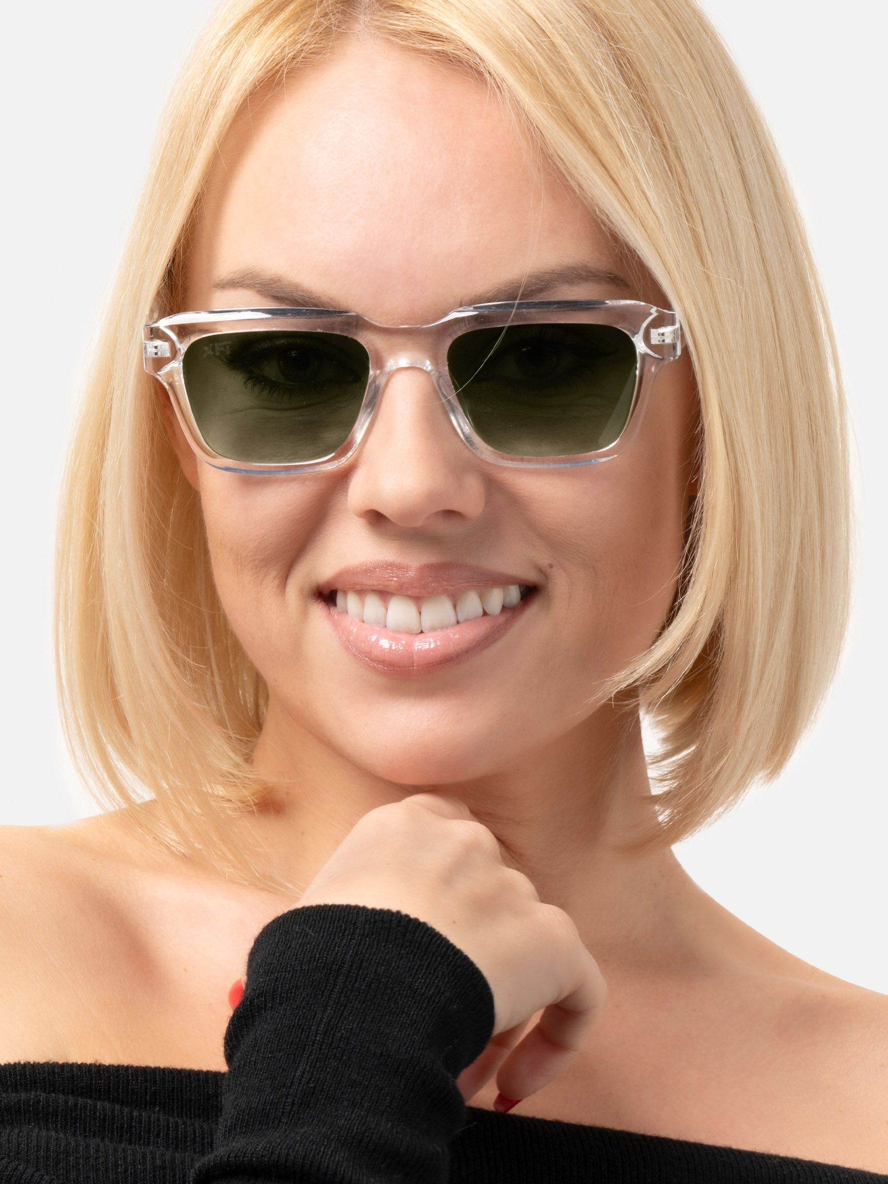 Primo piano di una donna con occhiali da sole trasparenti e lenti verdi. Sorride.