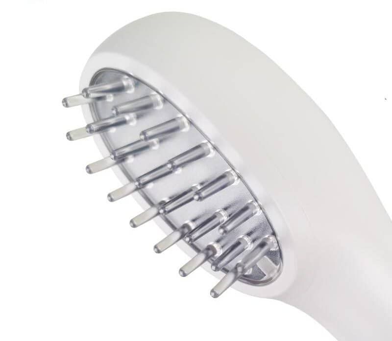 Primo piano della testa di un pettine laser bianco per la crescita dei capelli con denti trasparenti.