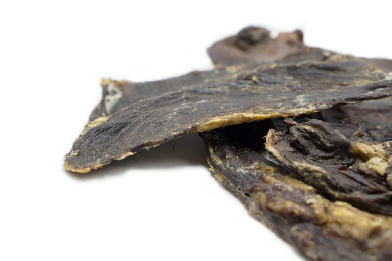 Primo piano di trippa di manzo essiccata, marrone scuro. Un pezzo si sovrappone a un altro.