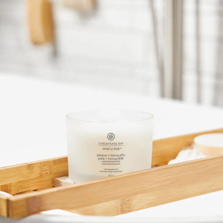 Candela in vetro bianco su vassoio di bambù. Testo: Chesapeake Bay, mind & body, peace + tranquility, Paix + tranquillité.