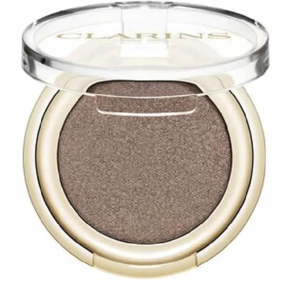 Ombretto Clarins rotondo, dorato. Coperchio aperto. Interno: Satin Taupe. Scritta Clarins.