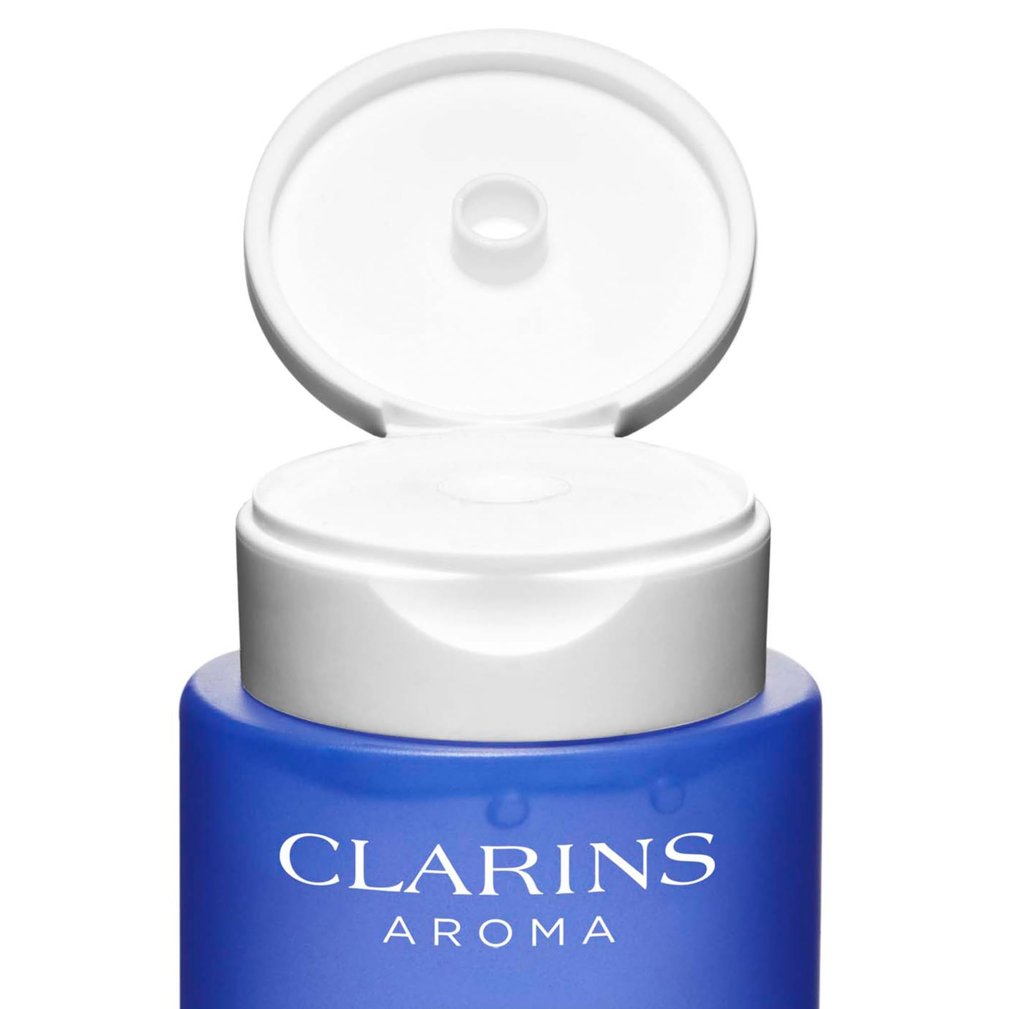 Primo piano del collo della bottiglia. Tappo bianco, corpo della bottiglia blu. Testo: Clarins Aroma.