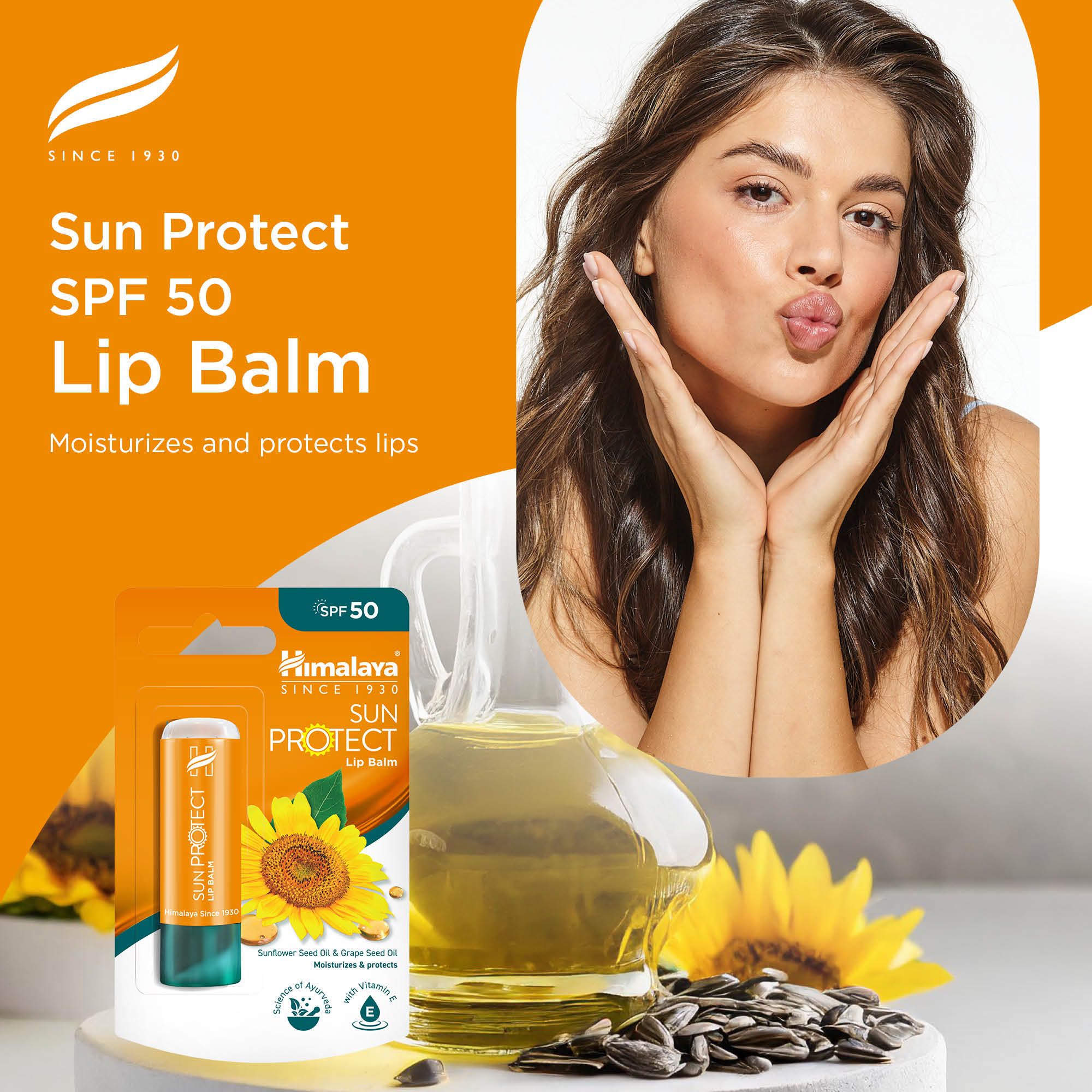 Balsamo labbra Himalaya Sun Protect SPF 50 nella sua confezione, con un bicchiere d'olio e girasoli.