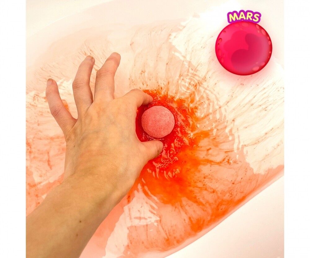 Mano tiene sfera Glibbi rosa in acqua rossa del bagno. Simbolo di Marte in alto a destra.