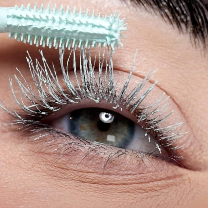 Occhio con ciglia. Spazzola applica il primer. Spazzola verde con prodotto sulle ciglia.