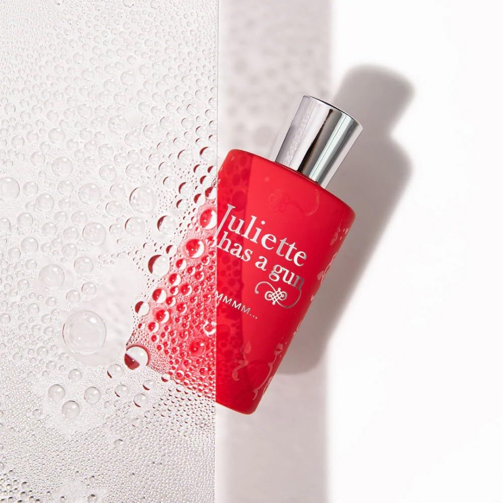 Flacone di profumo rosso con tappo argentato, parzialmente coperto da gocce d'acqua. Scritta: Juliette has a gun, MMMM...