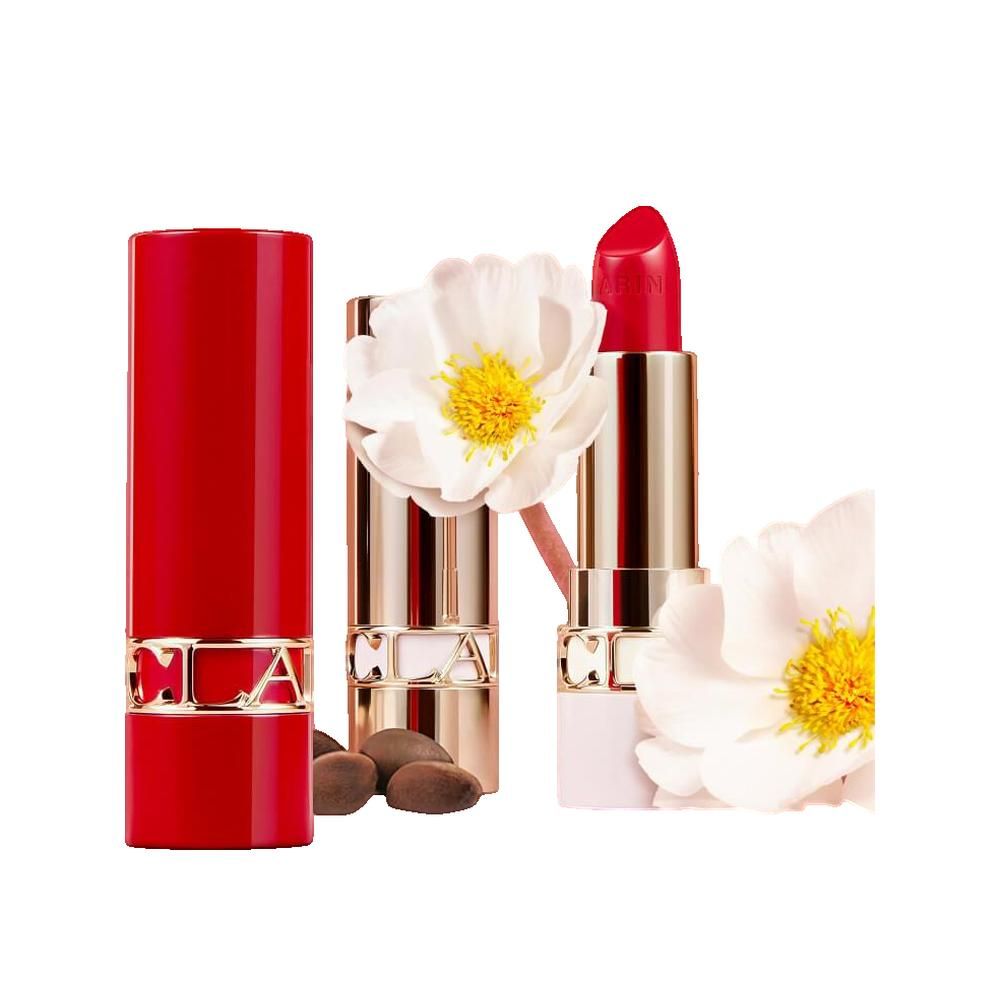 Rossetto rosso e astuccio dorato. Fiori e semi accanto. Marchio visibile.