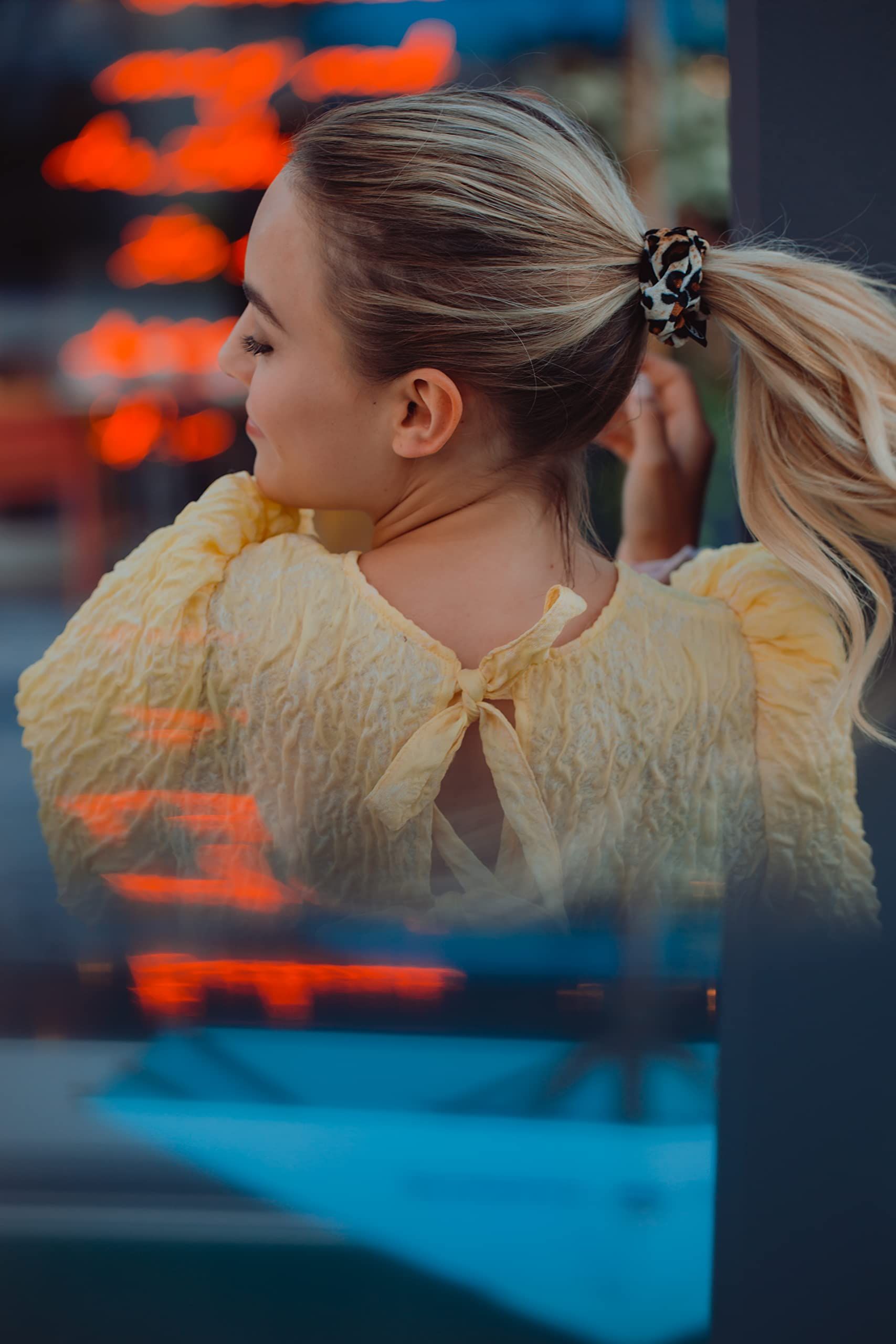Donna con capelli biondi che indossa un maglione giallo. Elastico per capelli con stampa leopardata tra i capelli.