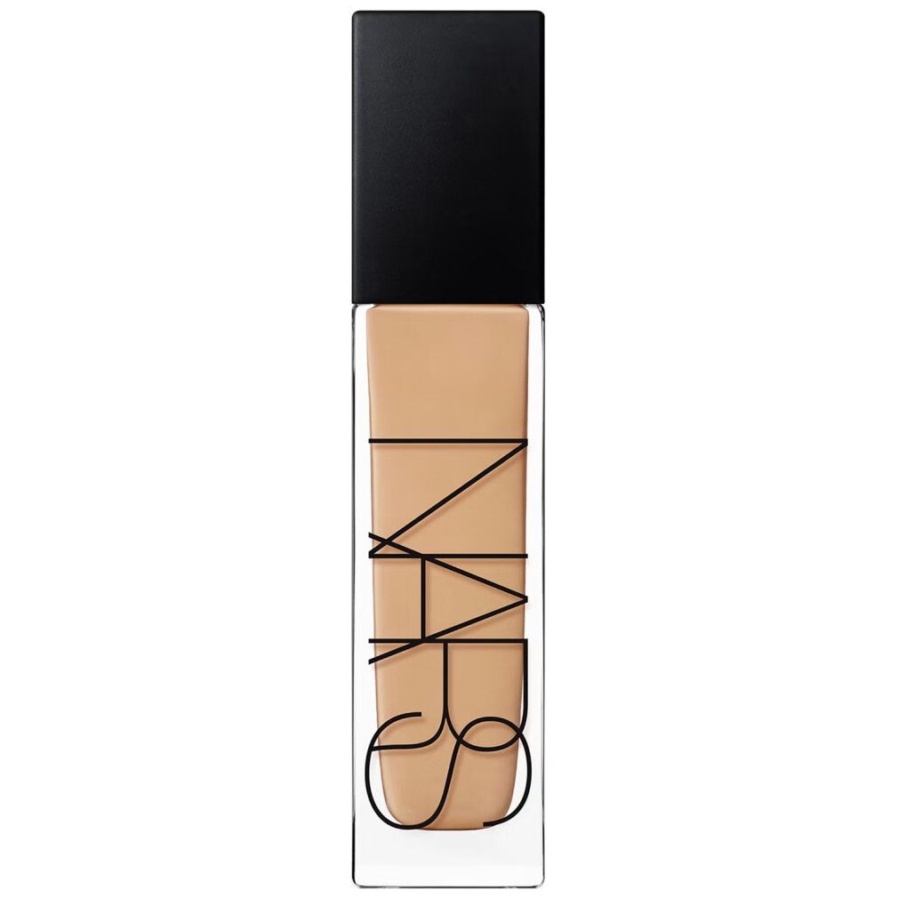 Flacone di fondotinta con tappo nero. Scritta nera: NARS. Flacone trasparente con fondotinta beige.