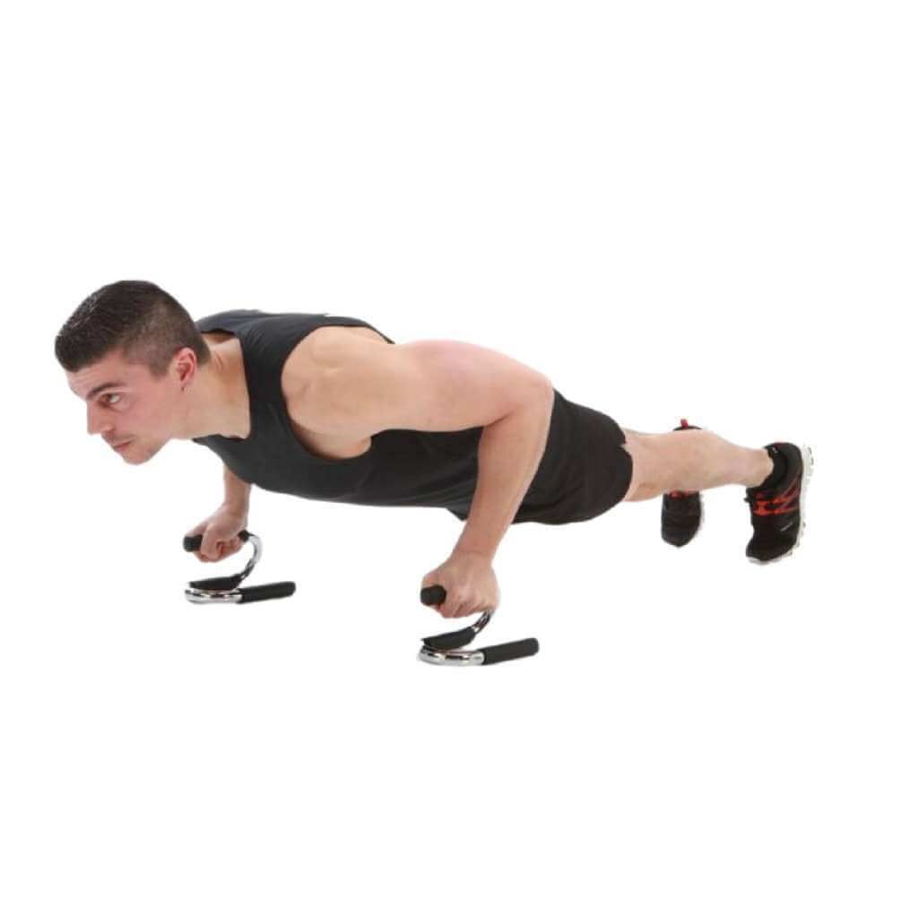 Uomo che fa flessioni con maniglie. Impugnature nere, struttura in metallo. La persona indossa abiti neri.