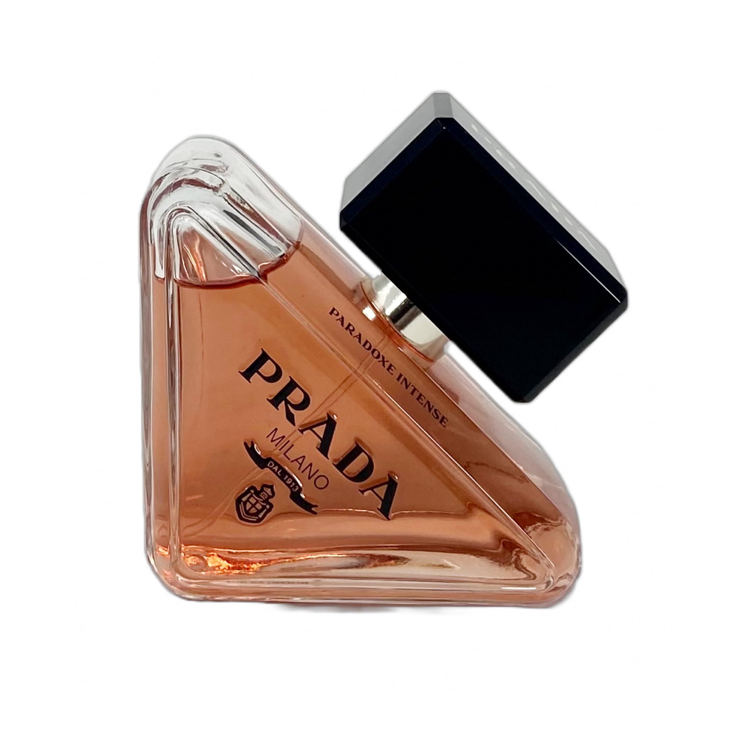 Flacone di profumo con tappo nero. Liquido rosa nel flacone. Testo: PRADA MILANO.