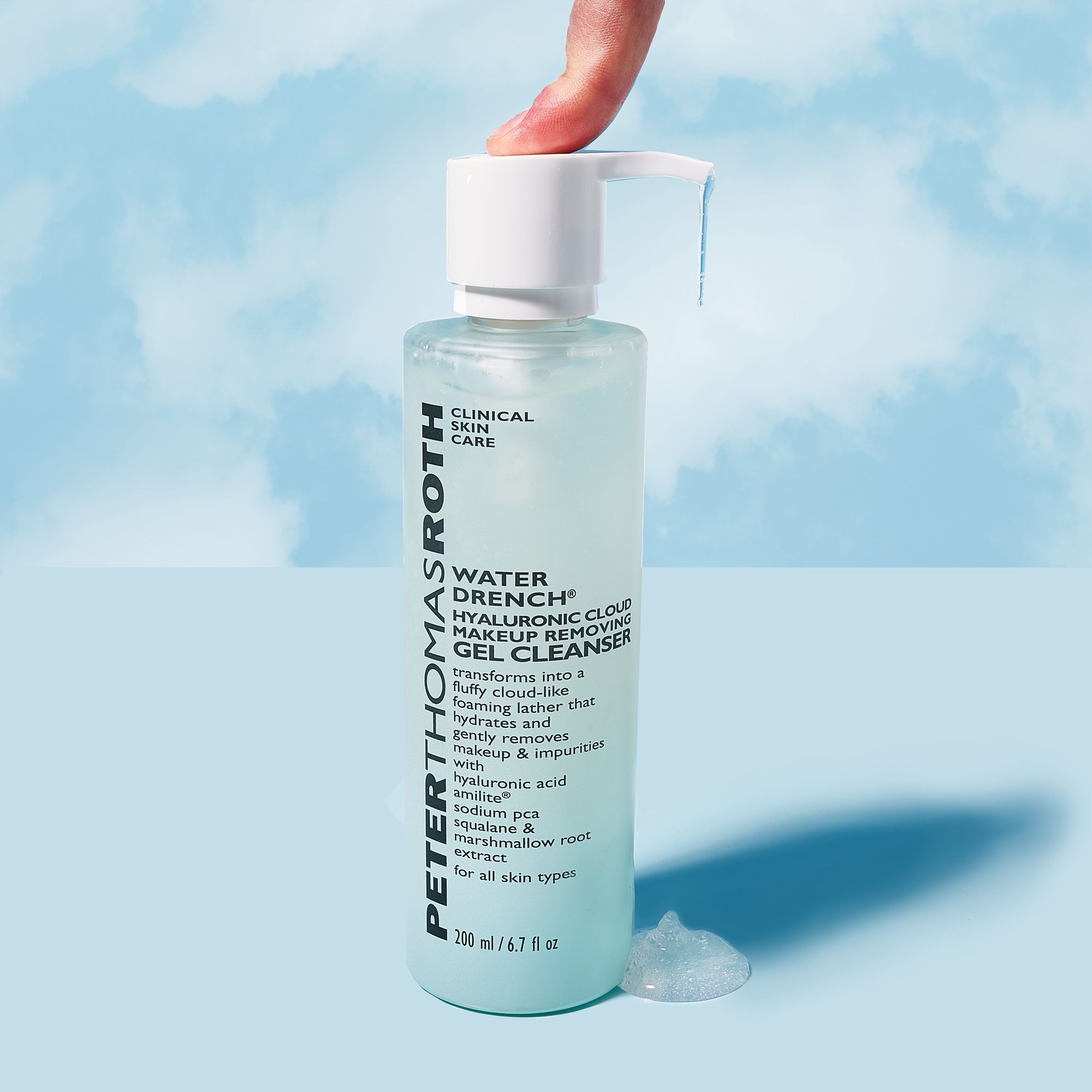Flacone di detergente per il viso con dosatore. Scritta: Water Drench Hyaluronic Cloud. Dito che tocca l'erogatore. Flacone azzurro.