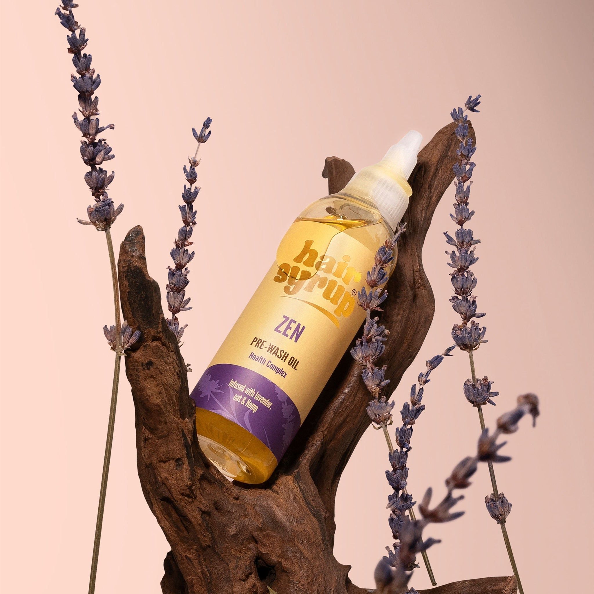 Una bottiglia di liquido giallo con etichetta. La bottiglia è appoggiata su un pezzo di legno, circondata da lavanda.