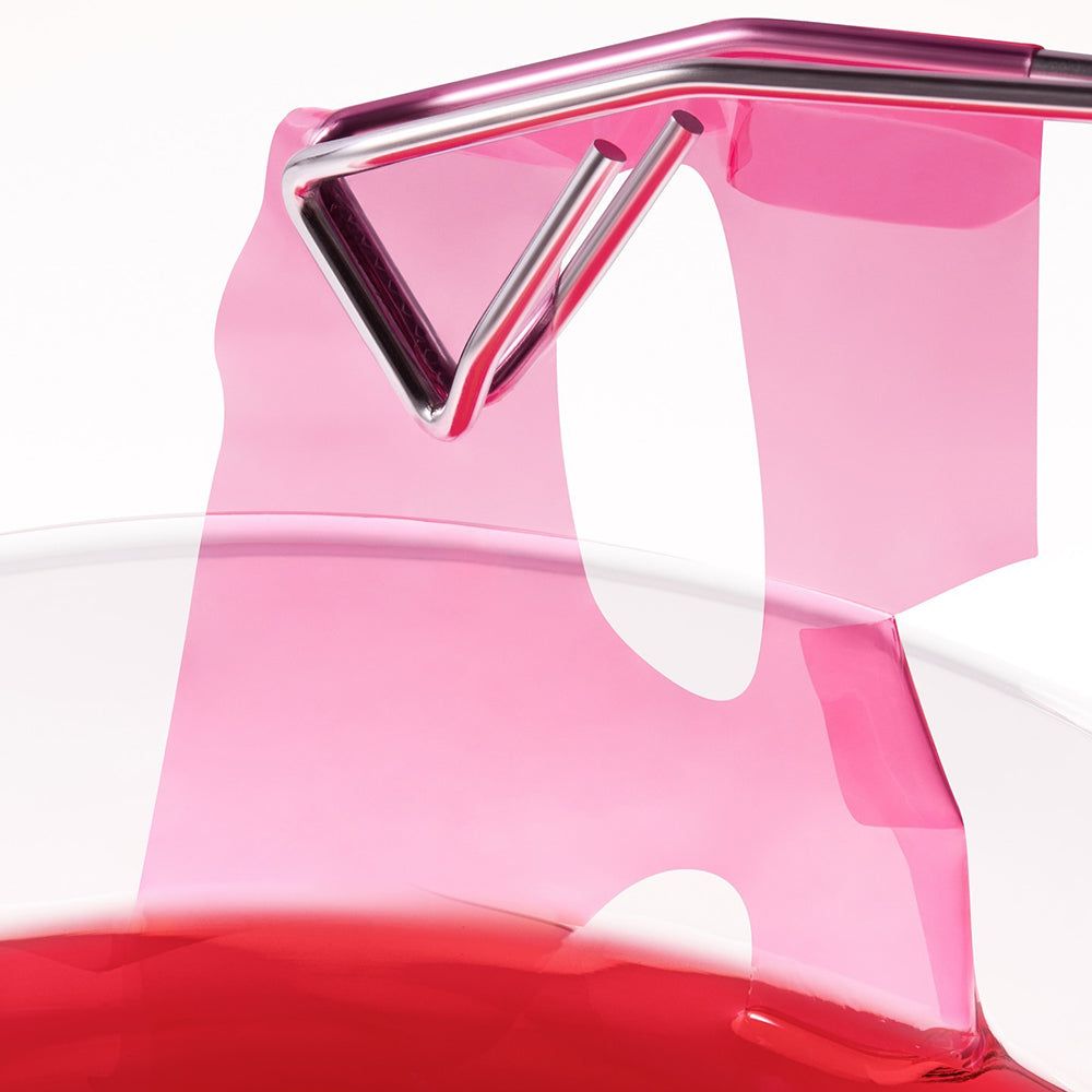 Oggetto rosa traslucido con cornice metallica argentata e liquido rosso.