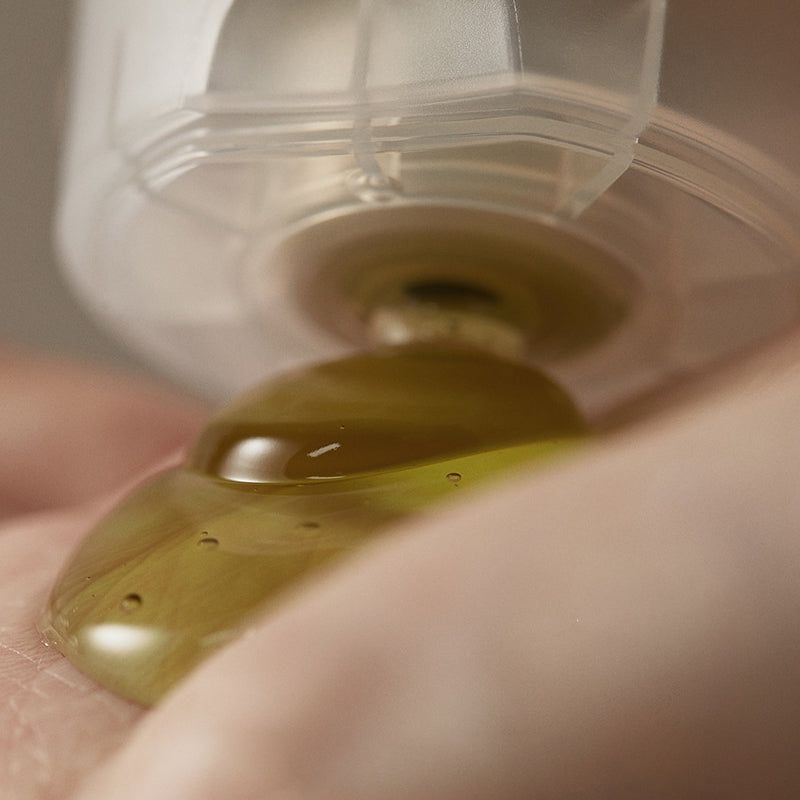 Primo piano di prodotto in gel che gocciola da un'apertura trasparente su un palmo.
