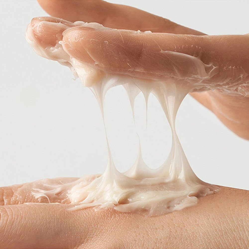 Mani con crema bianca. La crema è viscosa e forma dei fili.