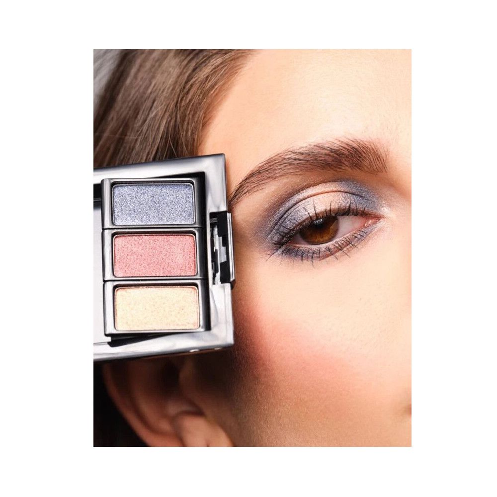 Palette con tre ombretti. Il prodotto è tenuto vicino a un occhio truccato. Colori: blu, rosa, giallo.