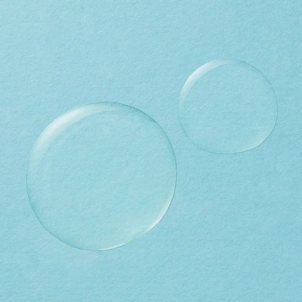 Due gocce di liquido su sfondo azzurro. Forma rotonda, consistenza trasparente.