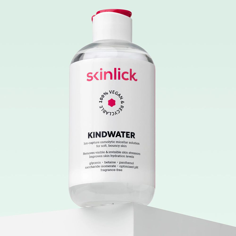 Flacone di SKINLICK Kindwater acqua micellare su un piedistallo. Liquido trasparente.