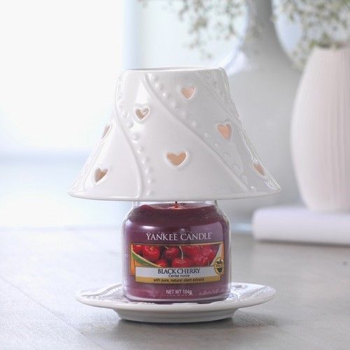 Candela Yankee Candle Black Cherry con paralume in ceramica bianca. La candela è su un sottobicchiere. Sfondo sfocato.