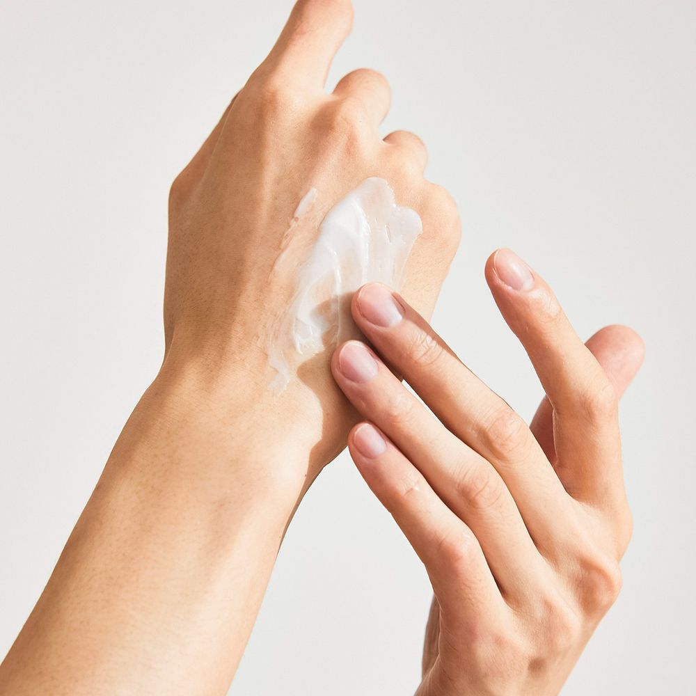 Mani, una strofinata con crema. Crema sul palmo. Pelle chiara. Sfondo bianco.