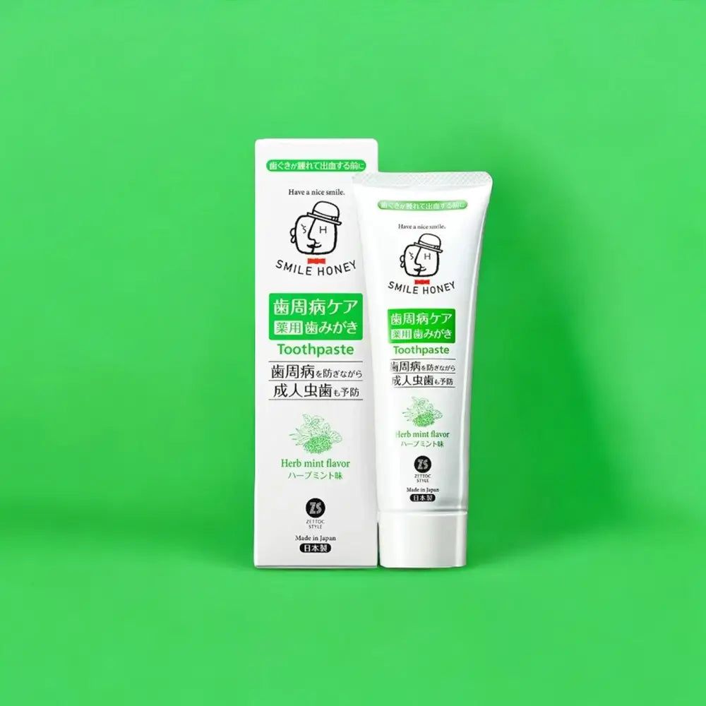Tubo di dentifricio e confezione bianchi, scritte verdi e nere. Scritta: SMILE HONEY, Toothpaste, Herb mint flavor.