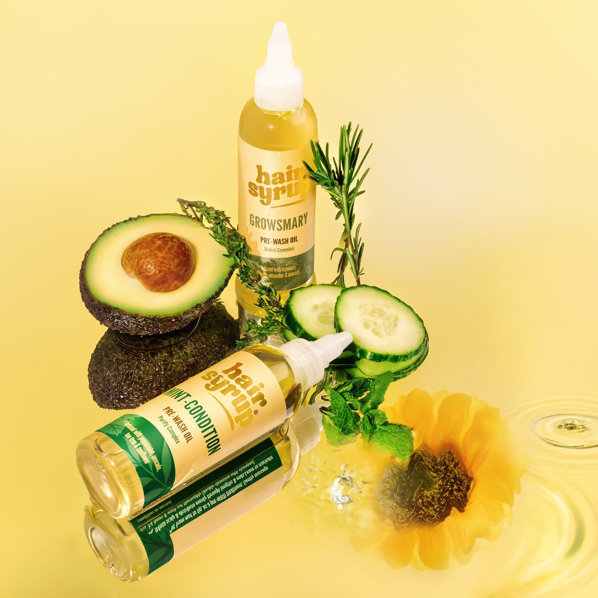 Due bottiglie « Hair Syrup Growsmary » con avocado, cetriolo, rosmarino e girasole. Su sfondo giallo.