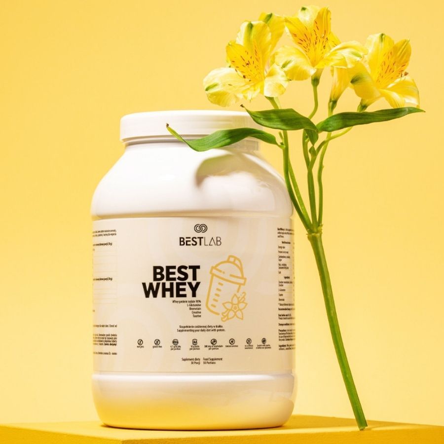 Barattolo di proteine Best Lab Best Whey bianco su sfondo giallo. Logo e scritta "BEST WHEY" sul davanti. Con fiori gialli.