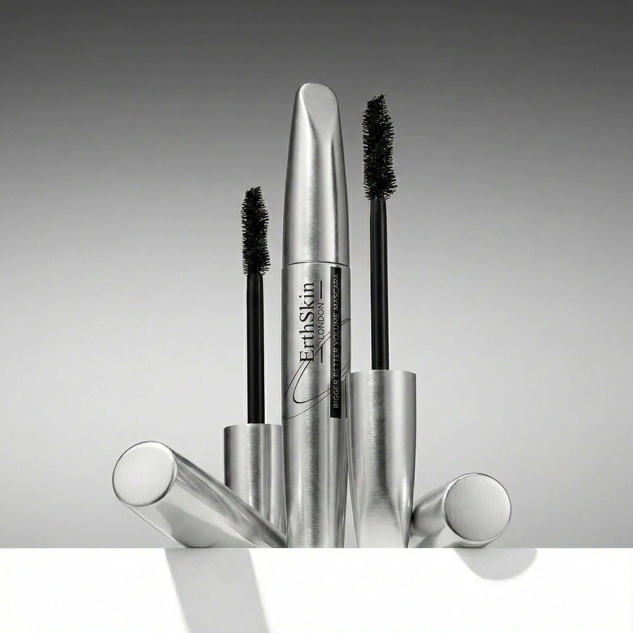 Tre confezioni di mascara argentate e applicatori con spazzola nera.