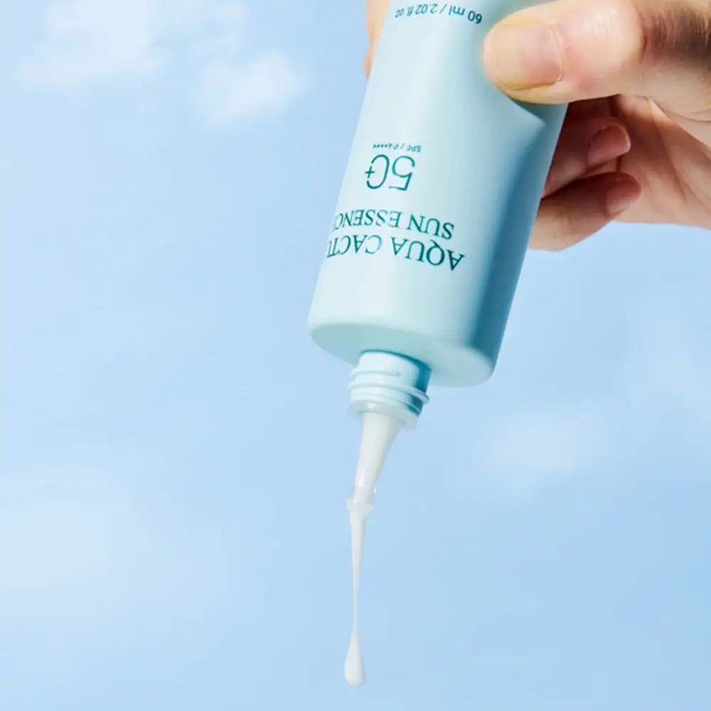 Flacone verde chiaro con applicatore bianco. Scritta: Aqua Cactus Sun Essence 50. Prodotto spremuto dal flacone.