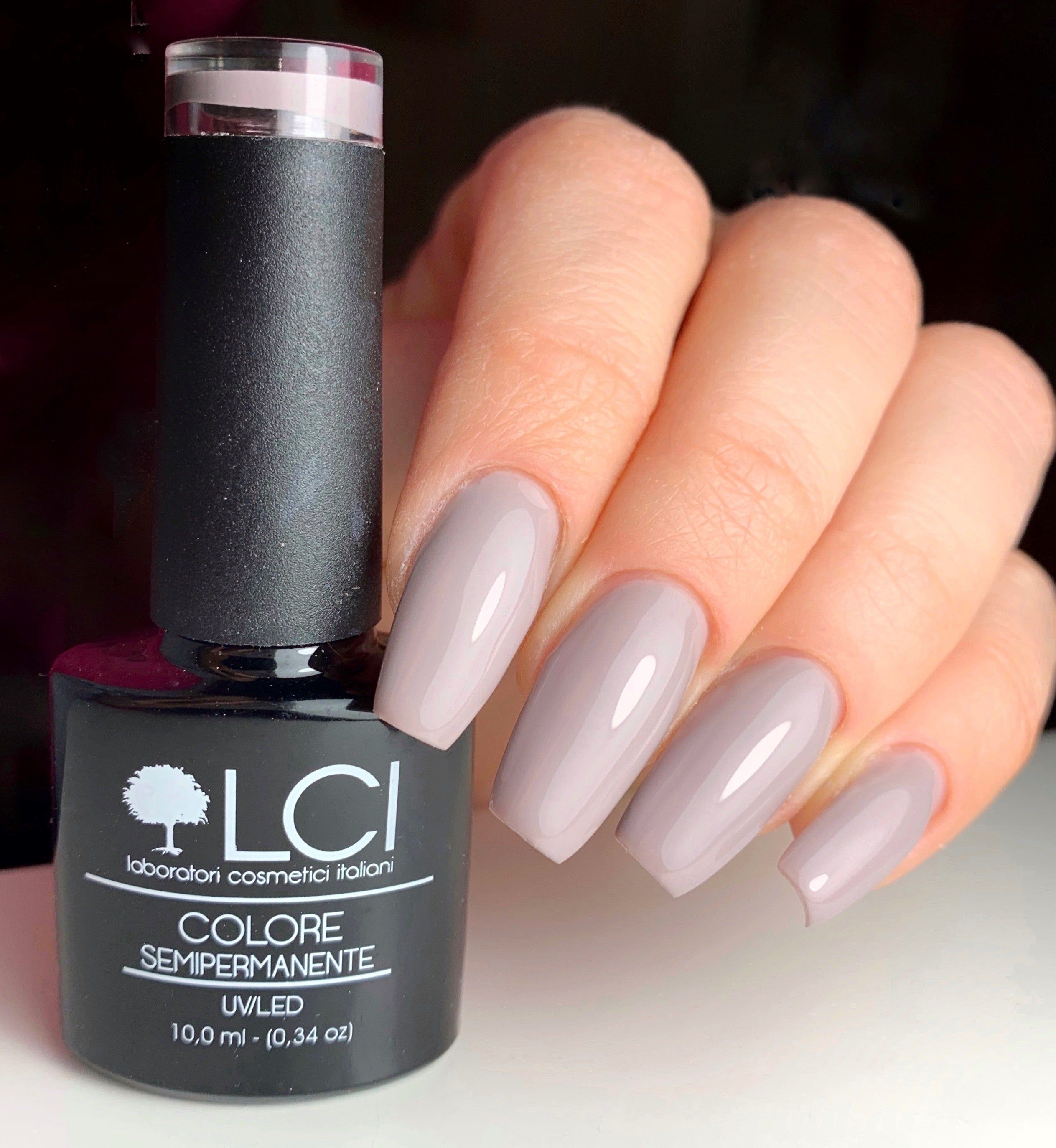 Flacone di smalto accanto a unghie smaltate grigio tortora. Scritta: LCI, Colore Semipermanente, UVLED 10,0 ml.