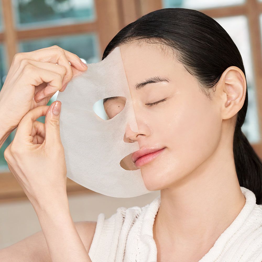 Donna con maschera per il viso. Una mano tiene la maschera, coprendo metà del viso.