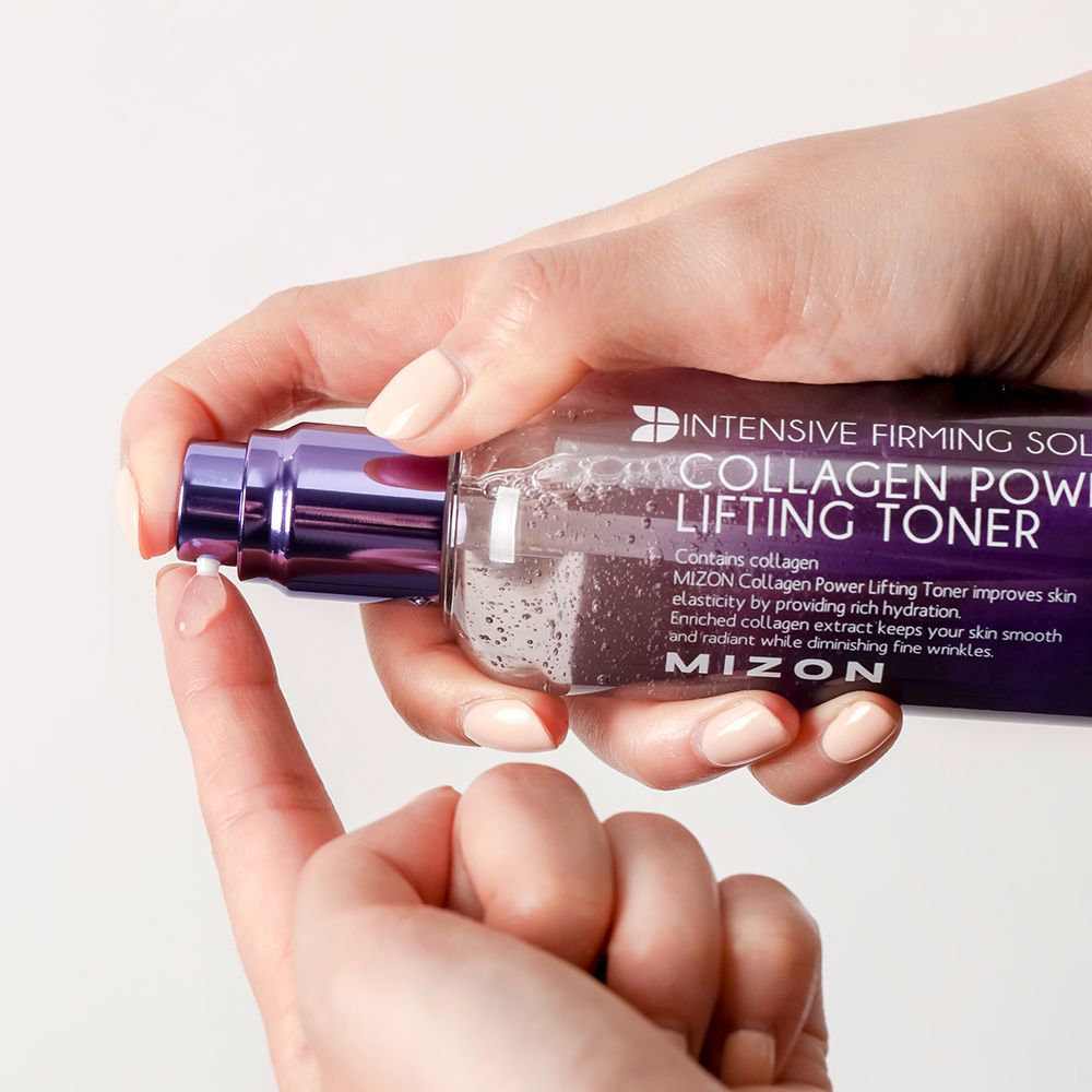 Mani che tengono una bottiglia di MIZON Collagen Power Lifting Toner. Il toner viene applicato sul dito.