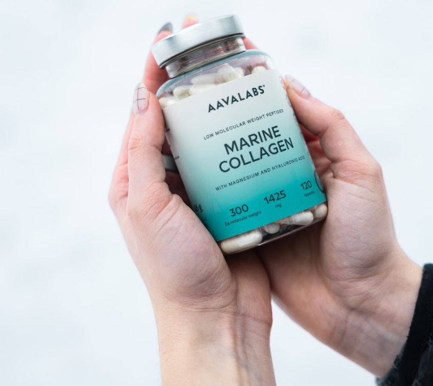 Mani che tengono una bottiglia di Aavalabs Marine Collagen nella neve.