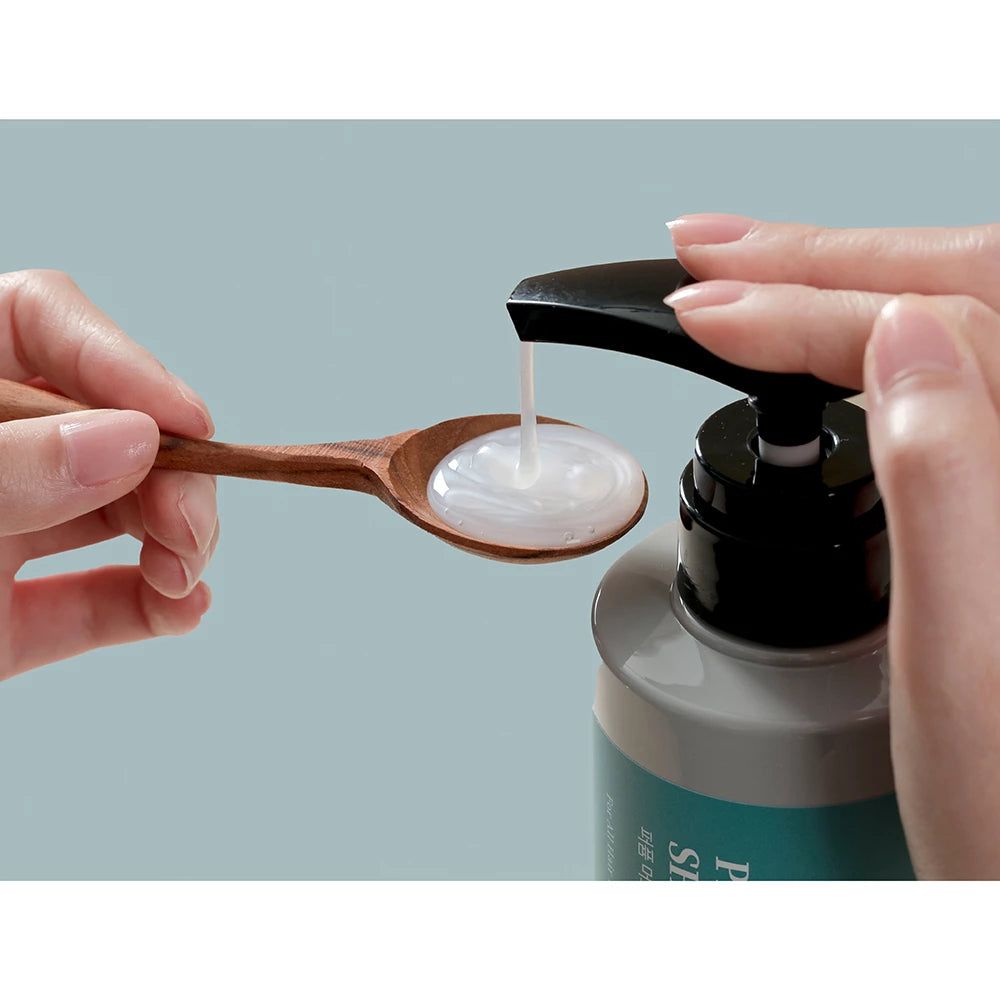 Shampoo versato su un cucchiaio di legno. Liquido chiaro.