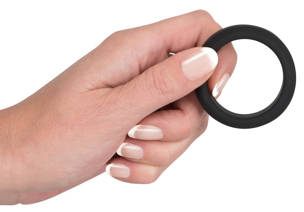 Mano che tiene un anello per pene nero in silicone.